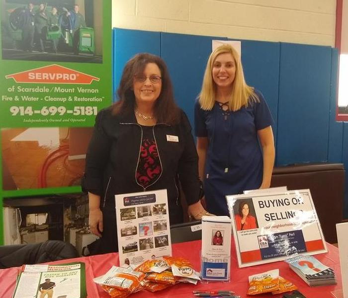 two women standing behind a career day booth