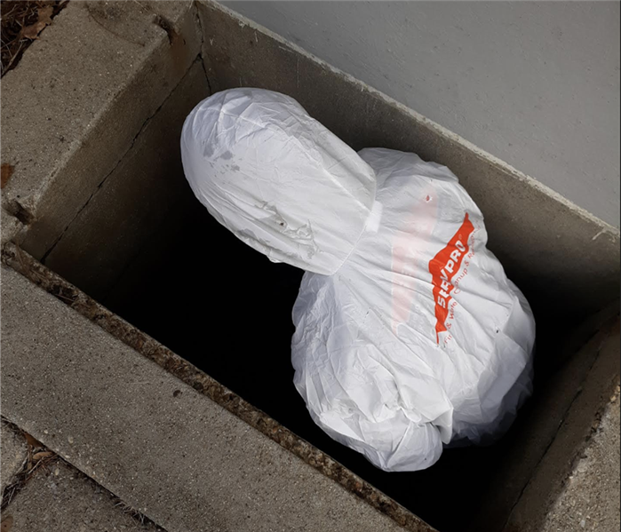 a man in a white suit standing in a crawlspace of a home