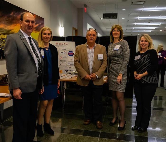 5 people standing inside a building next to a thank you sign