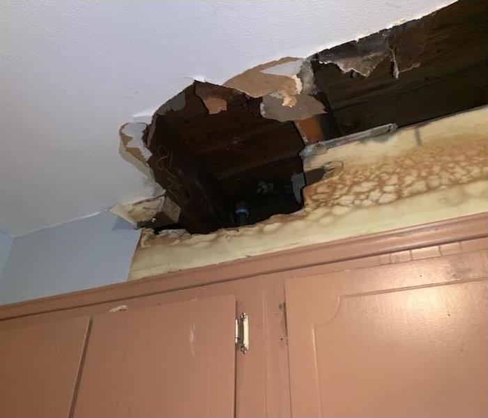Big hole in ceiling and water damaged walls.