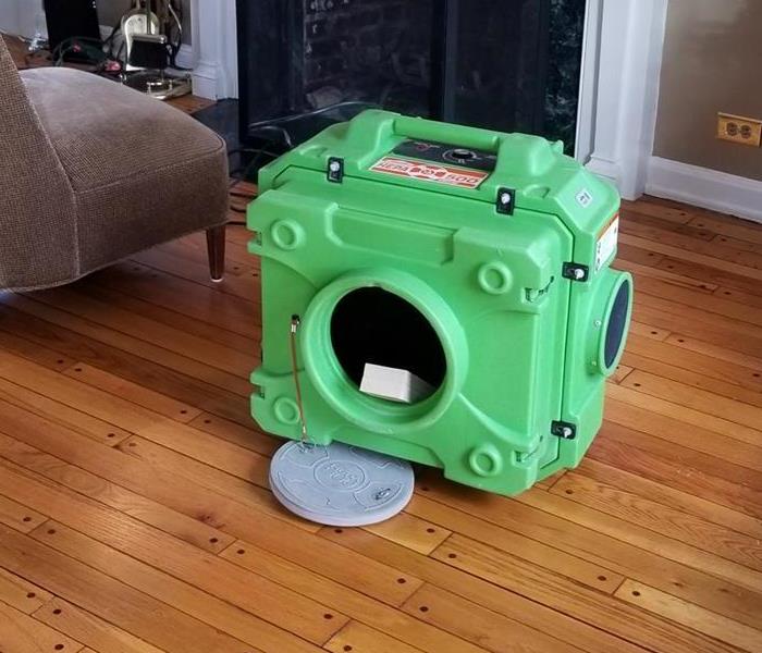 a piece of green equipment on the floor of a home by the fireplace