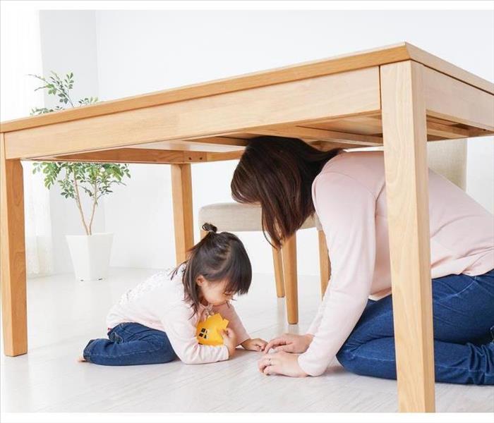 A mother and her daughter take refuge under a table
