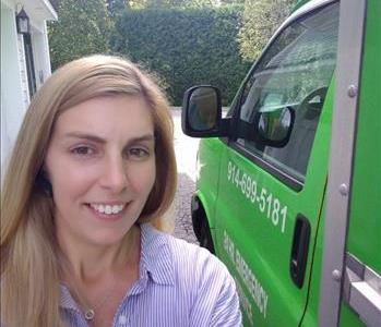 Female employee Traci Burrows smiling in front of SERVPRO truck!
